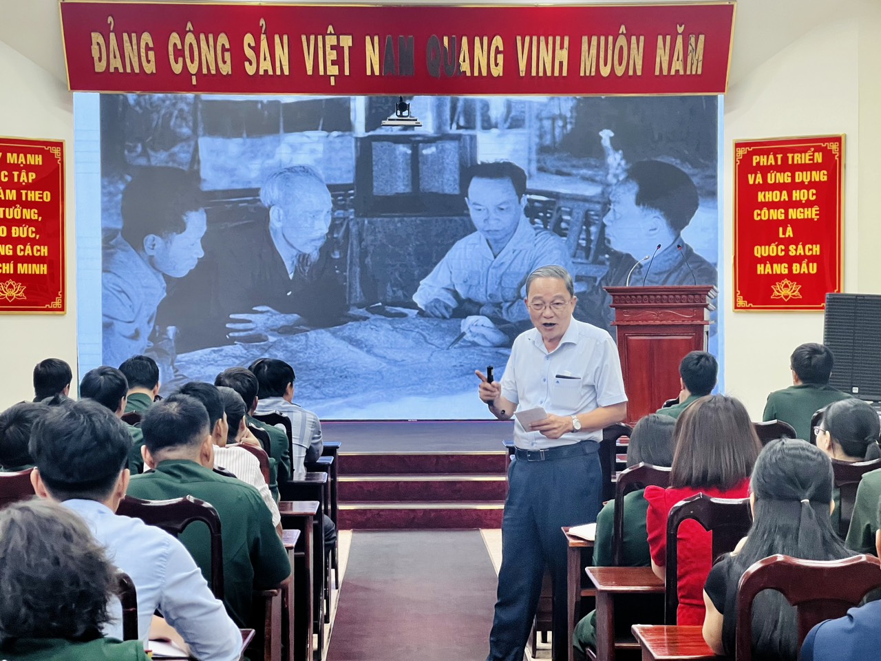 Description: A person standing in front of a group of peopleDescription automatically generated